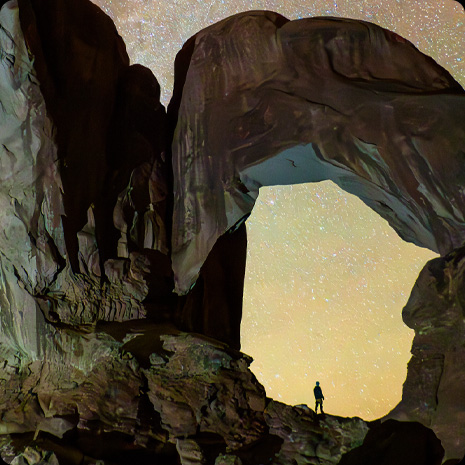 照片展示星空下的峽谷，峽谷中站著一個人。