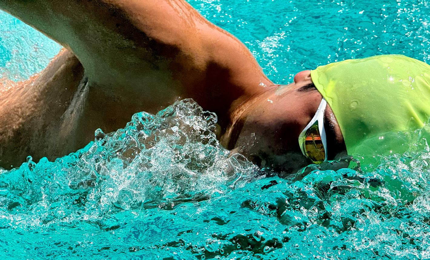 En detaljrik inzoomad bild på en simmare i en pool med vatten som stänker omkring honom