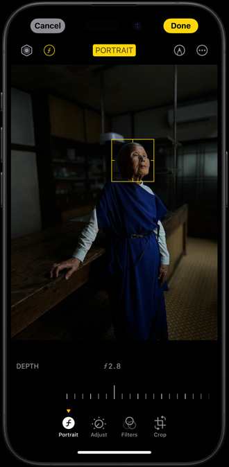iPhone 15 Pro s portrétom ženy zachytenom v slabo osvetlenom prostredí, kde má žena na tvári prispôsobiteľný ohniskový bod
