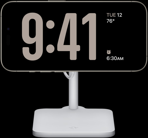 iPhone 15 Pro StandBy režīmā rāda pulksteni ar lieliem cipariem, kā arī datumu, temperatūru un tuvāko modinātāju